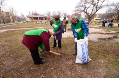 Belediye temizleyicileri, yaprakları tırmıkla temizleyip poşete dolduruyorlar. 21 Ekim 2017. Park Nivki. Kiev, Ukrayna