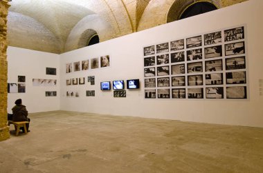 Yaşlı kadın bir bankta oturmuş, elinde resimlerle standa bakıyordu. Mystetskyi Arsenal Sanat Müzesi kompleksinin sergi odası. 5 Eylül 2021. Kyiv, Ukrayna