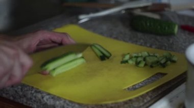 Aşçı mutfakta salatalık keser.