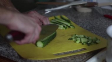 Aşçı mutfakta salatalık keser.