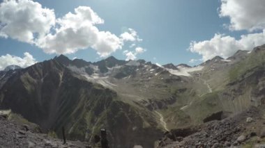 Elbrus Dağı 'ndaki karlı dağ manzarasının üzerinde bulutlar ve mavi gökyüzü
