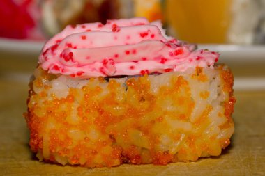 Suşi rulo somon, salatalık, krem peynir, havyar tobiko ve masago ile ahşap tahta