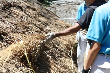 Bir zanaatkar sazdan çatıları açıklıyor.