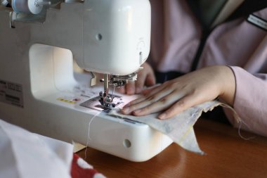 Dikiş makinesi kullanan bir kadın.