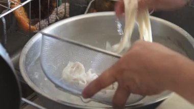 Haşlanmış udon eriştelerini durulayan bir kadın.