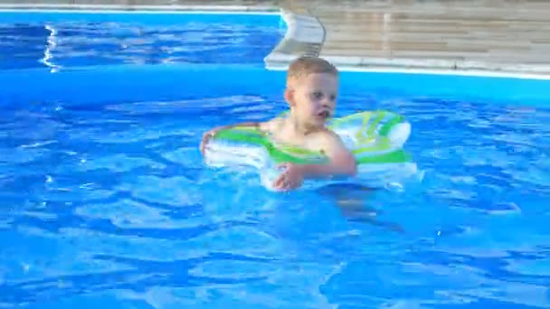 Menino flutuar no círculo inflável na piscina azul . — Vídeo de Stock