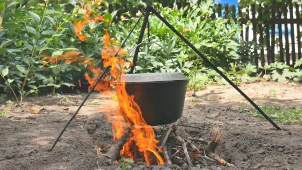 La olla de agua cuelga sobre el fuego. El agua hierve. Primer plano — Vídeos de Stock