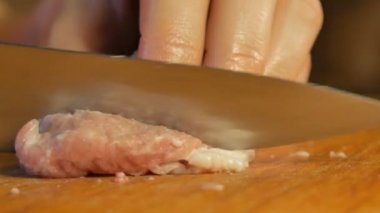 Kadın et kesme tahtası üzerinde küçük parçalar halinde bıçakla keser.