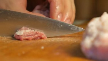 Kadın et kesme tahtası üzerinde küçük parçalar halinde bıçakla keser.