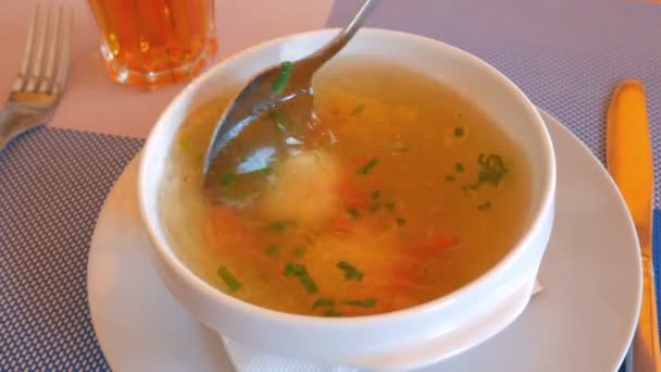 Cuillère fille empêchera la soupe avec des boules de viande et des pommes de terre sur une assiette blanche filante . — Video