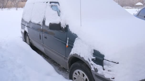 Voiture couverte de neige, sous une forte tempête hivernale. Voitures dans la cour sous la neige . — Video