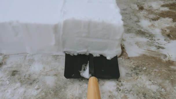 Uomo che spalava la neve dal sentiero. Rimuovere la neve con la pala dal marciapiede dopo la tempesta di neve. Cubi di neve . — Video Stock