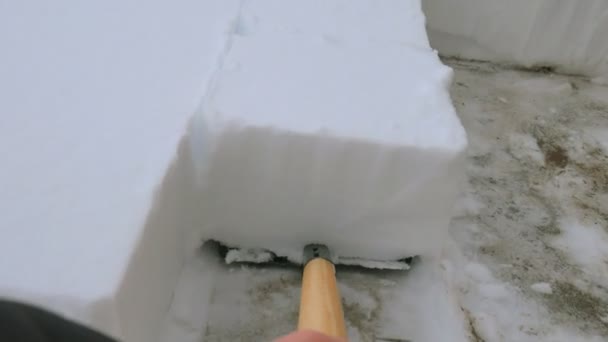 Un homme pelletant la neige du sentier. Enlever la neige avec une pelle à neige du trottoir après une tempête de neige. Cubes de neige . — Video