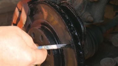 Adam tekerleği değiştirmeden önce siyah renkli pas fren kaliper boyaları.