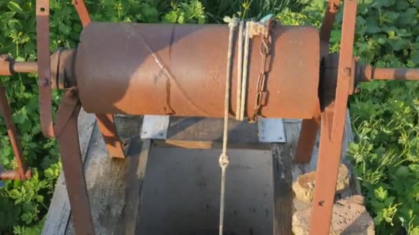 Mulher cai cadeia com balde em poço rústico para tirar água. Corrente de poço de água vintage fechar. Velha cadeia enferrujada da aldeia bem . — Vídeo de Stock