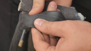 Bisikletçi veya tamirci delinmiş lastik bisikleti temizler. Ellerinizi ve bisiklet lastiğini kapatın. Bir adam delinmiş bir bisiklet tekerleği tamir.