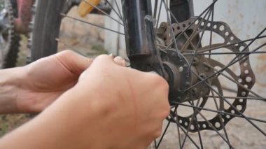 Kız bisikletin tekerleğikırıldı. Bisiklet tamiri. Bisikletçi bisikleti tamir ediyor. Tekerlekteki delik.