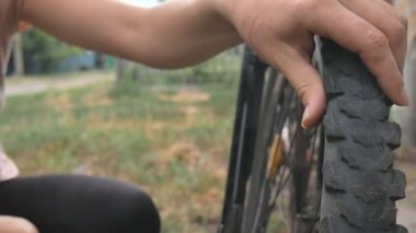 Kız bisikletin tekerleğikırıldı. Bisiklet tamiri. Bisikletçi bisikleti tamir ediyor. Tekerlekteki delik.