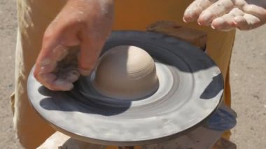 Heykeltıraş çömlekçiler sokakta çalışırken kilden sürahi yapıyorlar. Çarpık çömlekçiler çarkı.