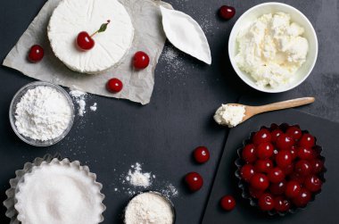 Süt ürünleri, un, şeker ve siyah arka plan, kopya alanı üzerinde kiraz