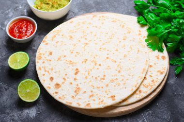 Sade tortilla domates Salsa, Guacamole ve koyu arka plan, leziz buğday ekmeği, Meksika yemeği üzerinde taze maydanoz ile
