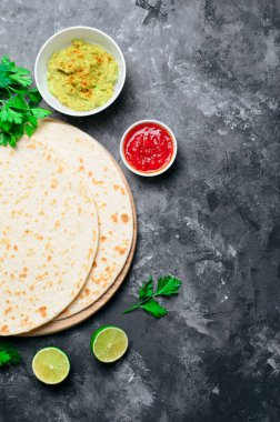 Sade tortilla domates Salsa, Guacamole ve koyu arka plan, leziz buğday ekmeği, Meksika yemeği üzerinde taze maydanoz ile