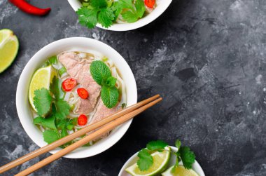 Geleneksel Vietnam çorba Pho Bo pirinç noodle, sığır eti ve otlar üzerinde koyu arka plan, Asya mutfağı