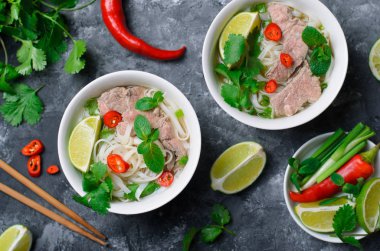 Geleneksel Vietnam çorba Pho Bo pirinç noodle, sığır eti ve otlar üzerinde koyu arka plan, Asya mutfağı