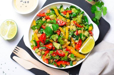 Taze sebze salatası, avokado, nohut, biber, salatalık, ıspanak ve giyinme, sağlıklı tahin ile Sağlıklı Vegan yemek yeme