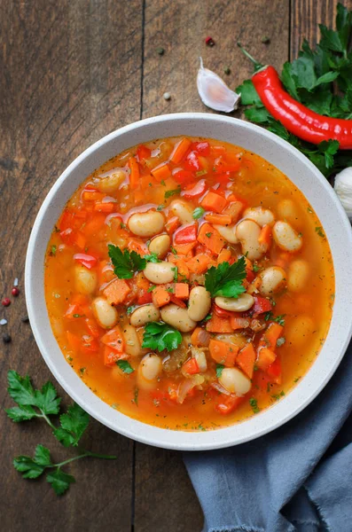 Vegetable Soup with White Beans, Homemade Soup on Dark Wooden Background, Vegetarian Food, Top View