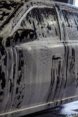 Araba yıkamada köpükle kaplanmış siyah araba.