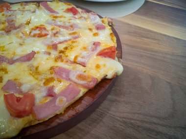 Pizza peynir jambon ve ahşap masa üzerinde yapardı.