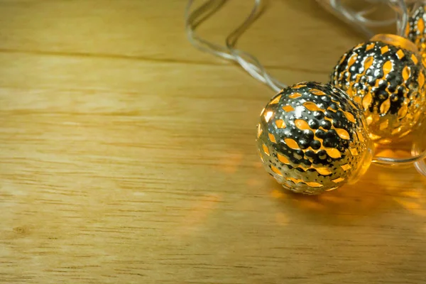 The Christmas gold lights ball decor on wood table.