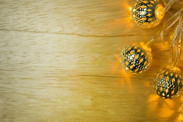 The Christmas gold lights ball decor on wood table.