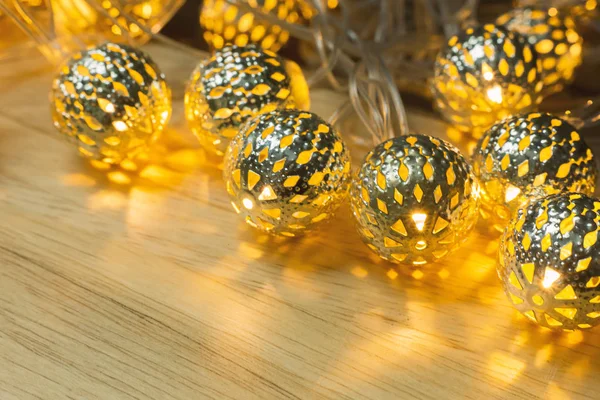 The Christmas gold lights ball decor on wood table.