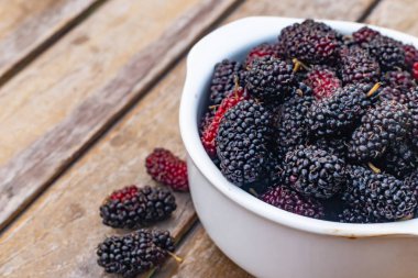  dut meyve ahşap masa üzerinde beyaz kase.