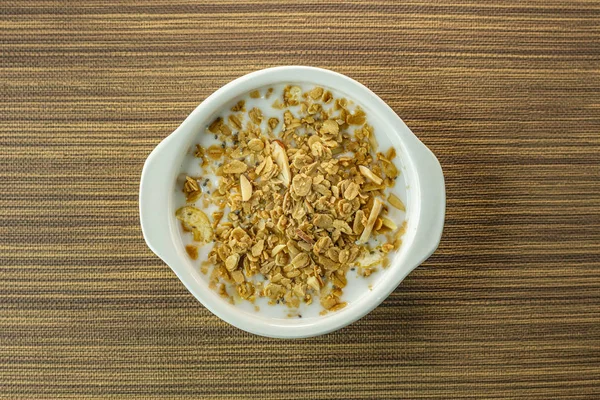 Ранкова їжа мигдалеві пластівці та молоко в білій мисці на дерев'яному столі — стокове фото
