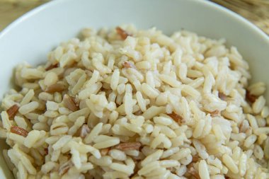 BROWN RICE beyaz kâse içinde ahşap masa üzerinde sağlıklı besinler için