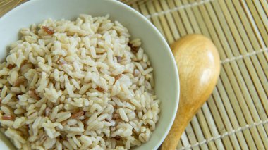 BROWN RICE beyaz kâse içinde ahşap masa üzerinde sağlıklı besinler için