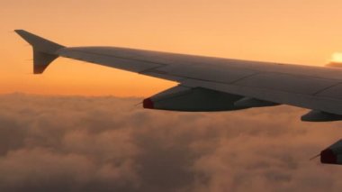 Günbatımı hacimsel gri bulutlar bir battaniyenin altında sırasında yüksekte yolcu uçağı olarak bir uçak kanadı görünümünü soars