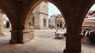 GUIMARAES, Portugal, 18 June 2025 - Largo da Oliveira Square features medieval arcades the Padrao do Salado monument and timber framed houses encircling lively cafe terraces in Guimaraes, Portugal