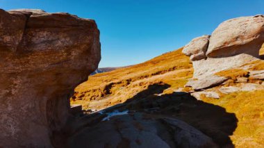 Mushroom shaped and anthropomorphic rock formations in a beautiful mountain range, displaying weathered stone columns, rounded caps, and curious silhouettes, under open sky across rugged terrain