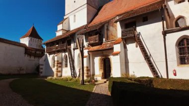 Harman Fortified Church, Harman, Transylvania, Romania, combines a white walled church, defensive ring, and robust tower, enclosing a calm courtyard that reflects centuries of community life