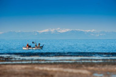 Kapalı kar dağlar ve balıkçı teknesi ile deniz kış görünümü