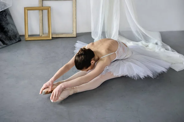 A jovem bailarina faz exercícios dobrados para trás, chegando aos pés — Fotografia de Stock