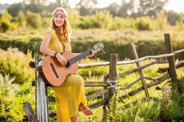 Femme portant un style bohème, jouant de la guitare sur le terrain à la guerre — Photo