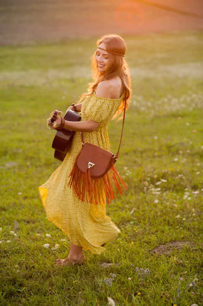 Krásná hippie dívka s kytarou tanec na poli při západu slunce — Stock fotografie