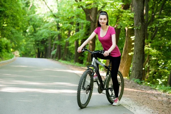 Žena Cyklistka Kole Asfaltové Cestě Lese Slunečného Dne — Stock fotografie