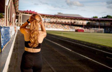 Genç sporcu kadın spor için içeri girer, arkadan bakar.