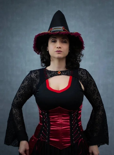 Siyah ve kırmızı kostümlü ciddi bir cadı, kameraya bakıyor. Cadılar Bayramı için ideal, cadılık, gizem ve şeytani sihir. Kopya alanı ile dikey stüdyo portresi.